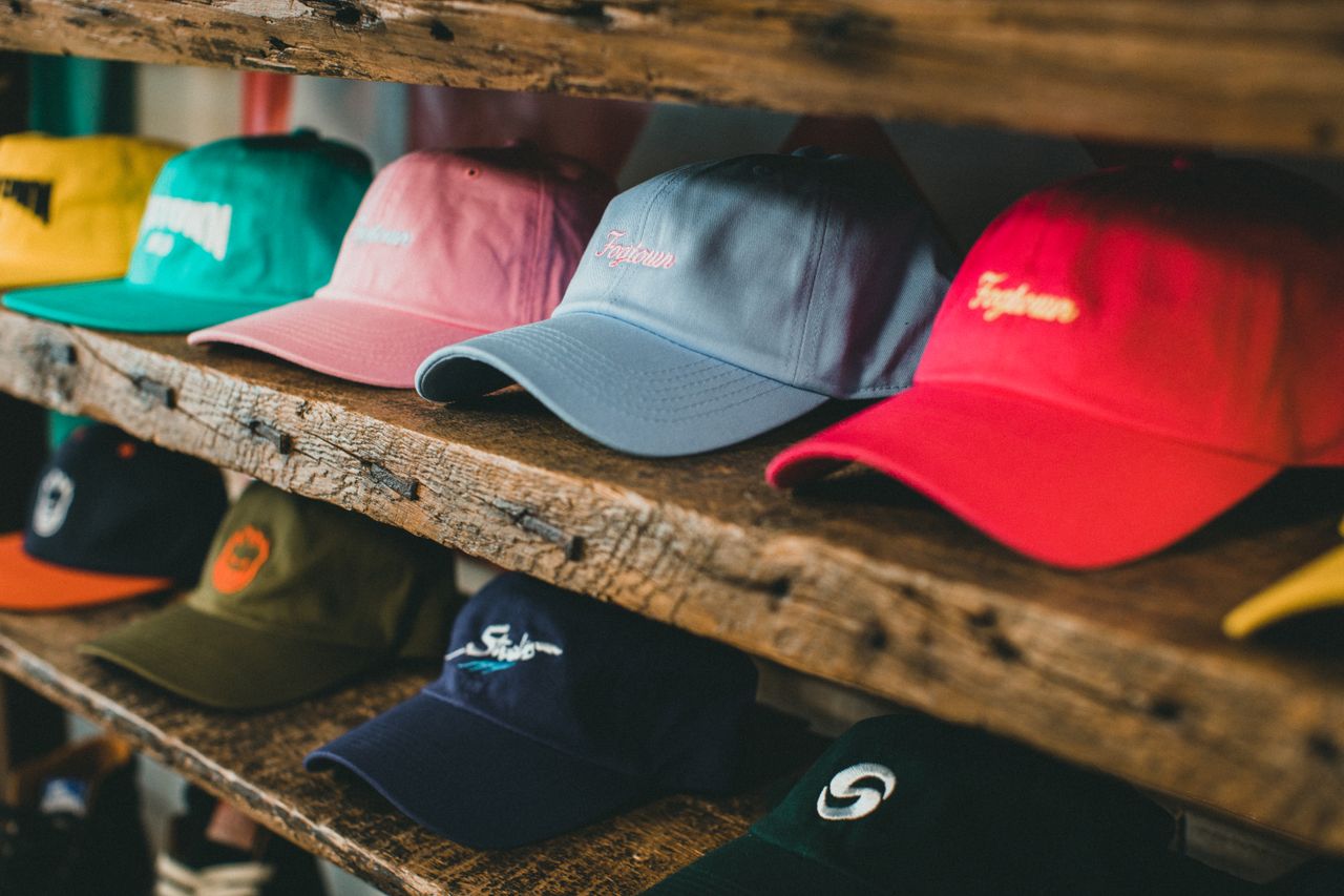 A variety of colorful baseball caps arranged on rustic wooden shelves in a store setting.